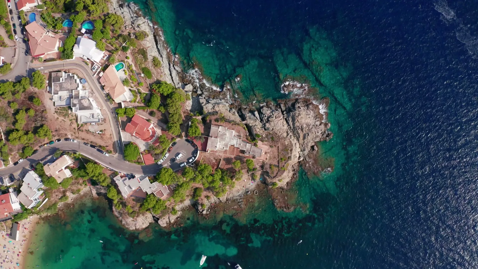 Vista aérea de la costa de Mallorca: aguas turquesas, casas junto al mar y una barca